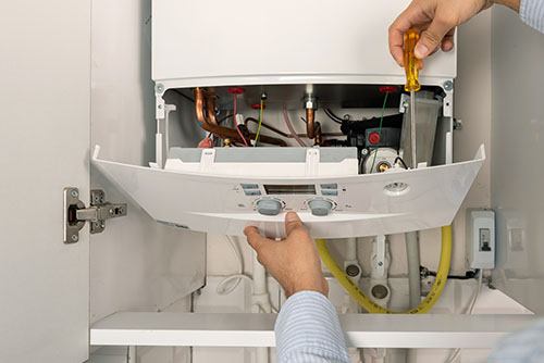 Heating technician repairing a residential boiler in Goleta