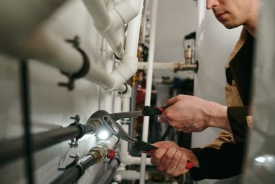 Technician inspecting commercial plumbing pipes in Goleta