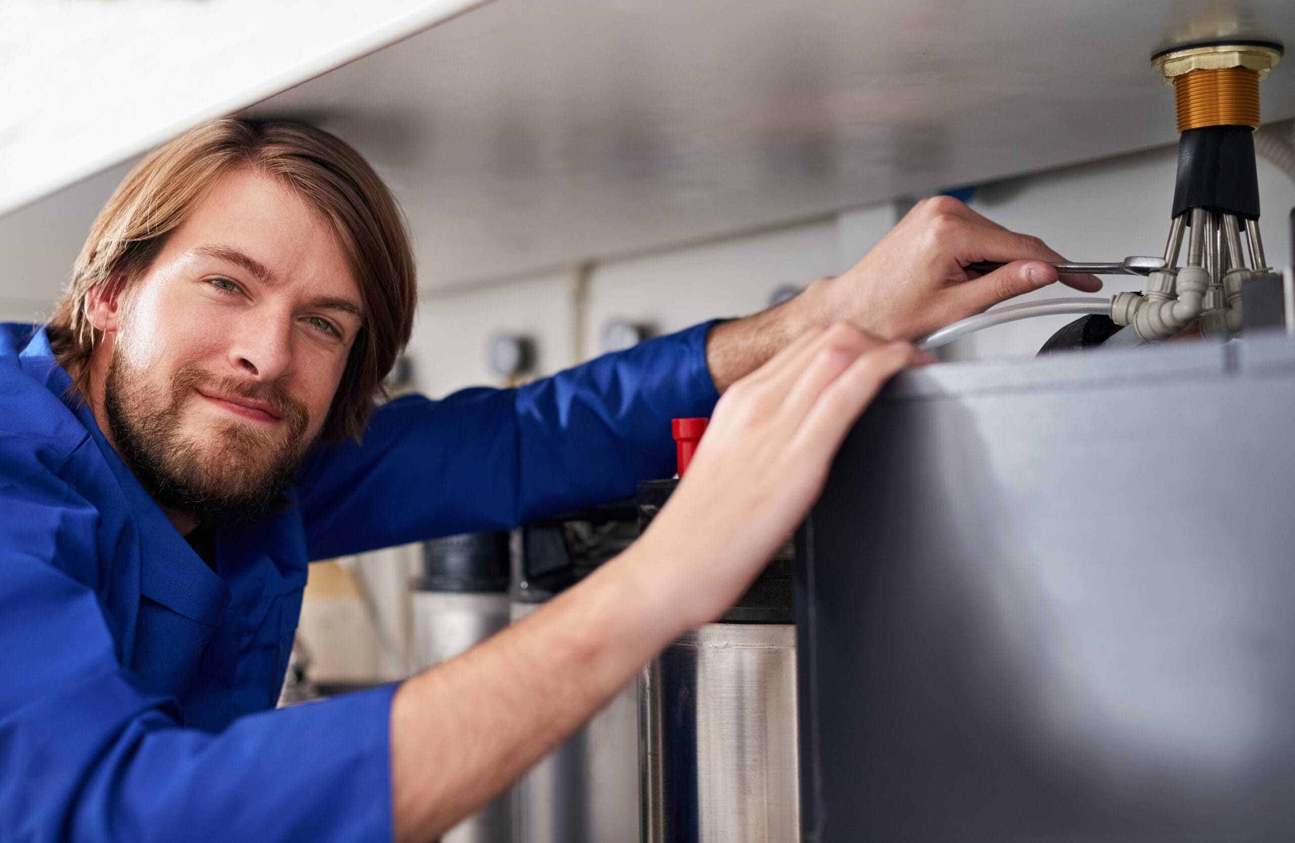 Technician servicing a residential water heater tank in Goleta